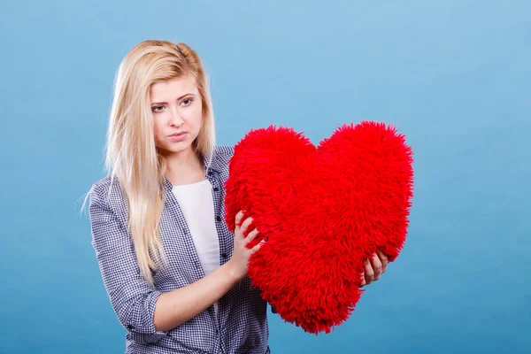 O femeie tristă care ține perna roșie în formă de inimă — Fotografie, imagine de stoc