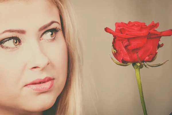 Frau mit roter Rose im Gesicht sieht melancholisch aus — Stockfoto