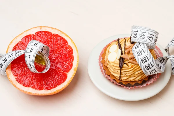 Grapefruit and cake with measuring tape. Diet