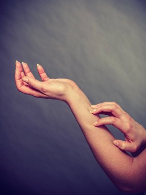 Dişi kaşınan kolunu alerji isiliği ile kaşıyor.