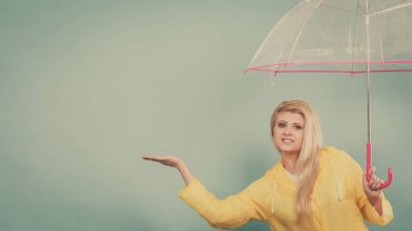 Hava kontrol şemsiye tutan yağmurluk giyen kadın