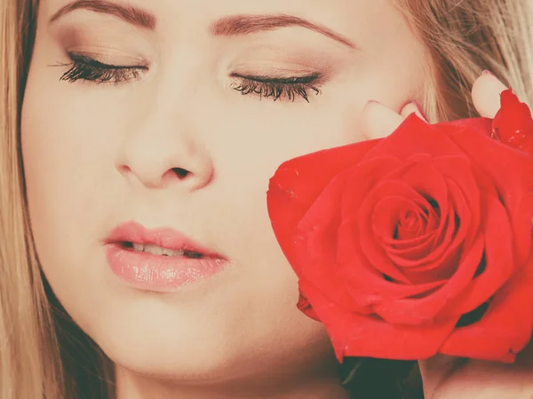 Closeup žena držící červená růže poblíž obličej. — Stock fotografie