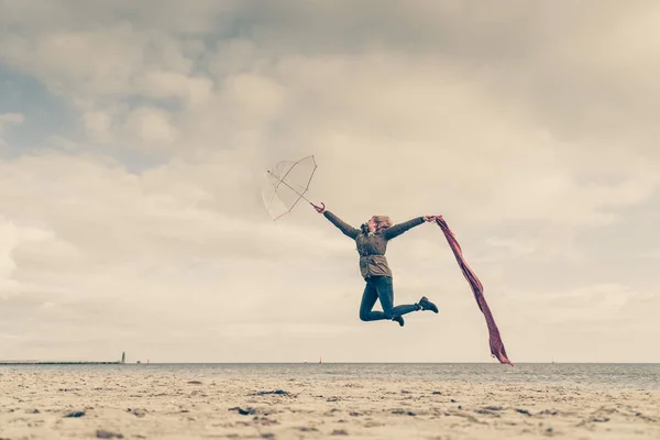 Счастливая женщина прыгает с шарфом на пляже — стоковое фото