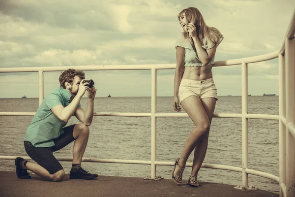Ungt par i kärlek tar foton på piren i havet. — Stockfoto
