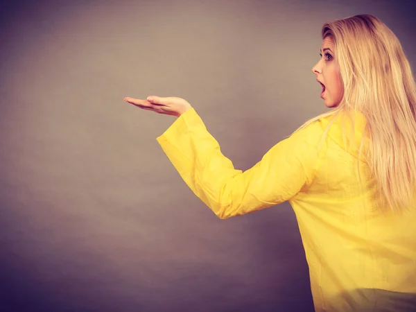Mujer sorprendida vistiendo impermeable amarillo mostrando la mano — Foto de Stock