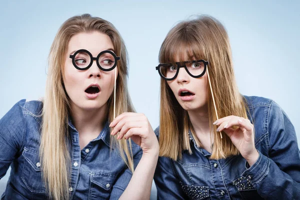 Dos mujeres felices sosteniendo anteojos falsos en palo — Foto de Stock