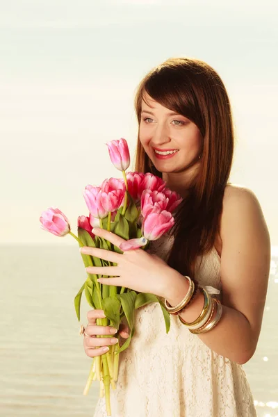Porträtt av kvinna med rosa blommor på stranden — Stockfoto