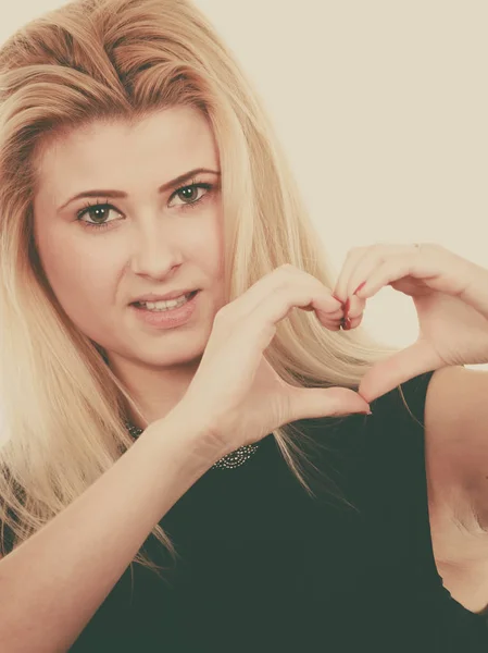 Blonde woman making heart symbol with hands