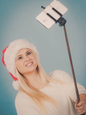 Santa şapka alarak fotoğrafını selfie stick kullanarak kız