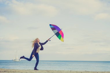 Kadın ile renkli şemsiye plajda atlama