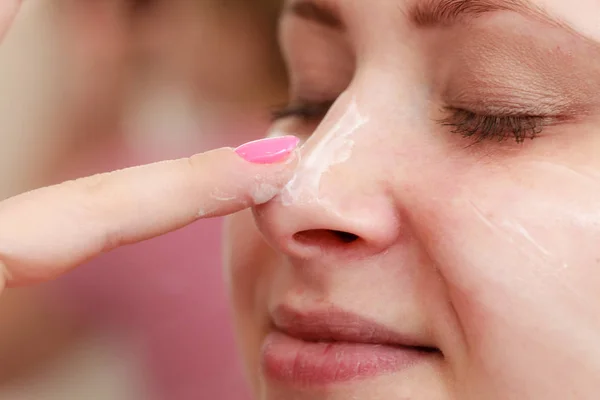 Mujer aplicando crema facial con el dedo —  Fotos de Stock