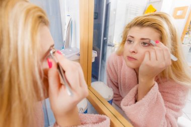 Kaşlarını cımbızla temizleyen kadın.