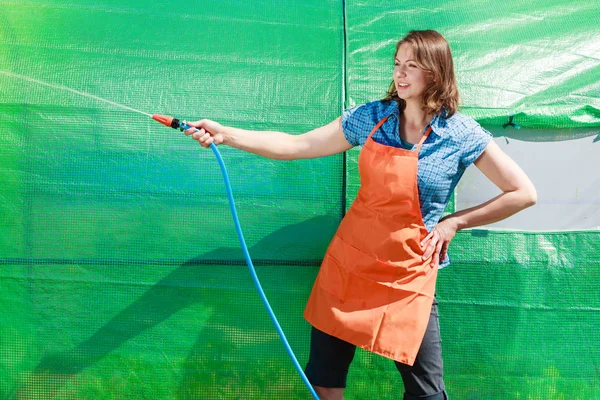 Woman watering the garden with hose — Stock Photo, Image