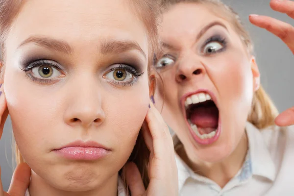 Яростная девушка кричит на своего друга, самка закрывает ему уши — стоковое фото