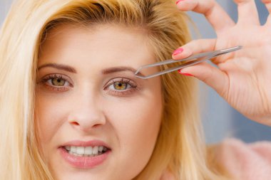Kaşlarını cımbızla temizleyen kadın.
