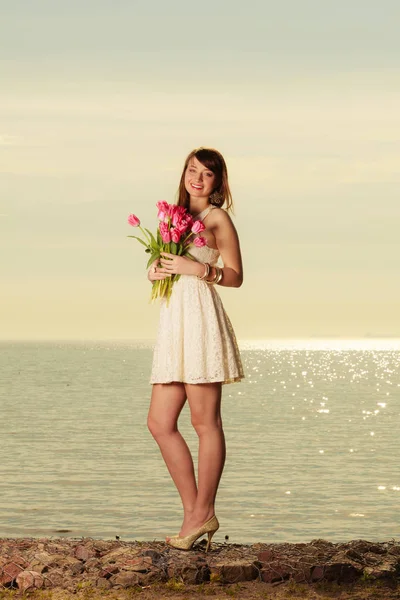 Hermosa mujer sosteniendo ramo de flores en la playa —  Fotos de Stock