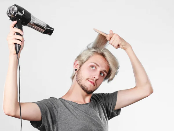 Junger Mann trocknet Haare mit Haartrockner — Stockfoto