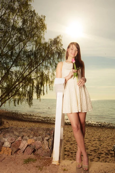 Vrouw stond op strand houden van roze tulp — Stockfoto
