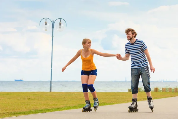 Pareja joven en patines de ruedas montando al aire libre — Foto de Stock