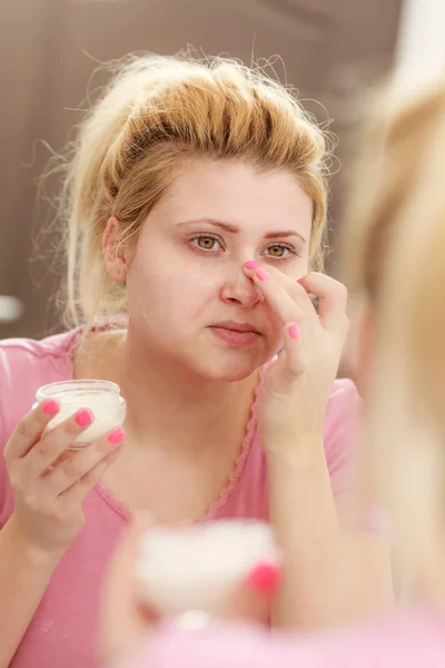 Mujer aplicando crema facial con el dedo —  Fotos de Stock