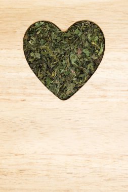 Isırgan yaprakları kalp ahşap yüzeyde şeklinde kurutulmuş