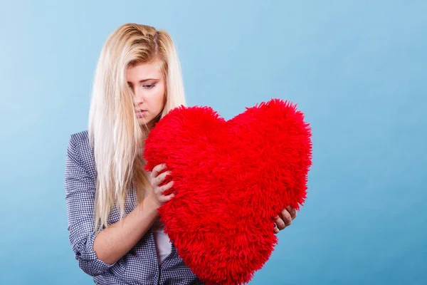 Kırmızı yastık kalp şeklinde tutan üzgün kadın — Stok fotoğraf