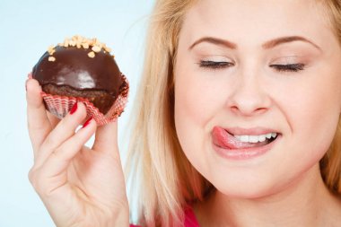 Çikolatalı kek tutan kadın ısırmak üzere.