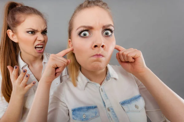 Яростная девушка кричит на своего друга, самка закрывает ему уши — стоковое фото
