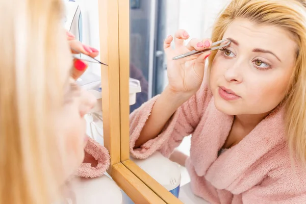 Woman tweezing eyebrows depilating with tweezers — Stock Photo, Image