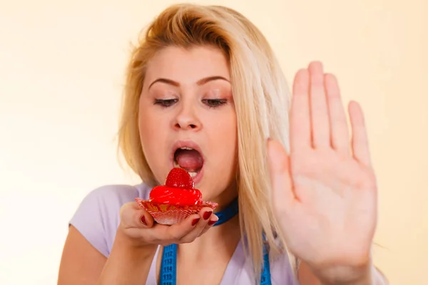 Frau mit Maßband hält Cupcake und zeigt Anschlag — Stockfoto