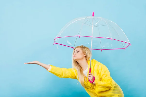 Mujer vistiendo impermeable sosteniendo paraguas comprobando el clima — Foto de Stock