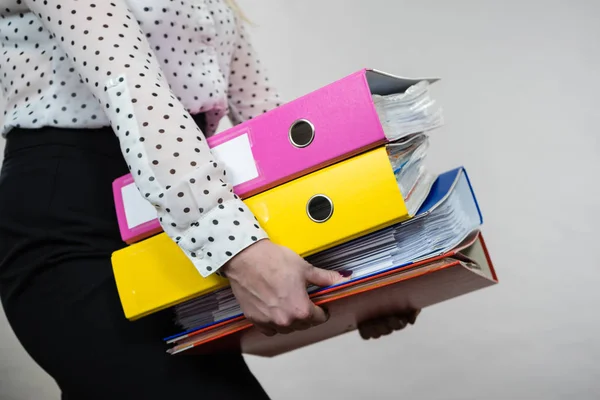 Woman holding heavy colorful binders with documents