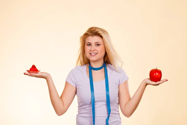 Woman choosing between apple and sweet cupcake — Stock Photo, Image