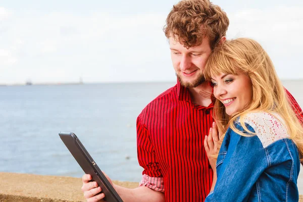 Young couple with tablet by seaside outdoor