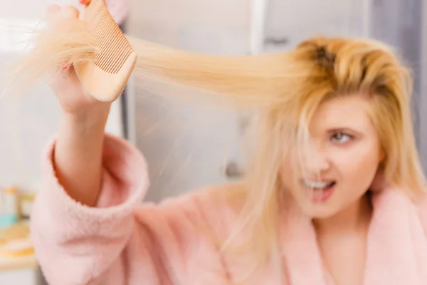 Mujer conmocionada usando bata cepillándose el pelo —  Fotos de Stock