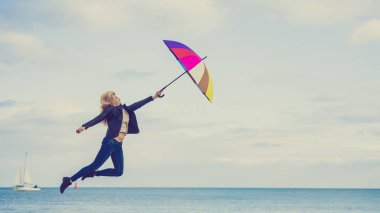 Kadın ile renkli şemsiye plajda atlama