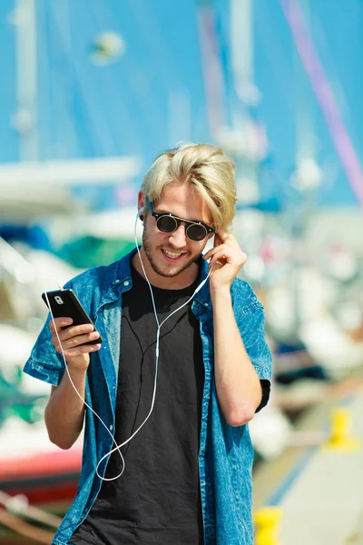 Blonde man in sunglasses listening to music — Stock Photo, Image
