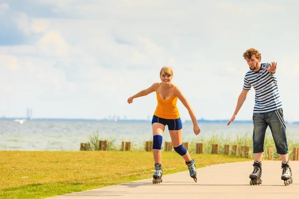 Jovem casal em patins andando ao ar livre — Fotografia de Stock