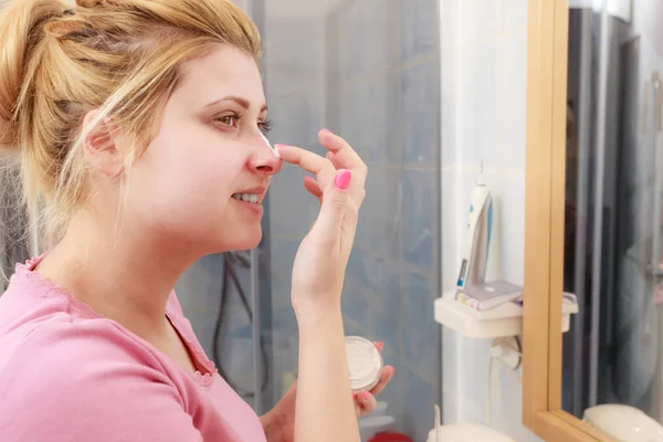 Mujer aplicando crema facial con el dedo — Foto de Stock