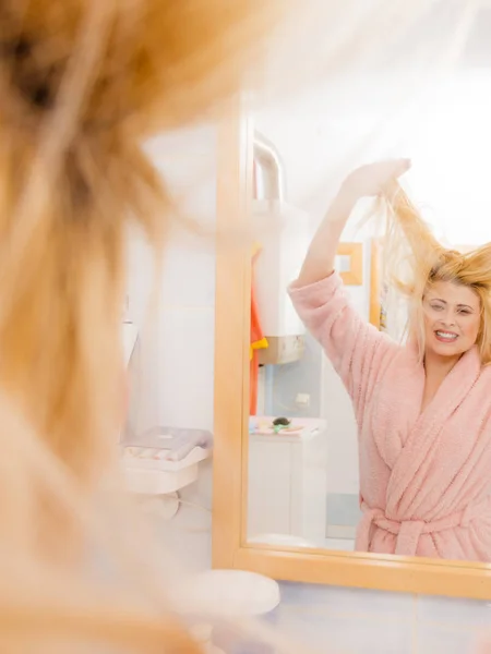 Frau blickt auf ihr sehr wirres blondes Haar — Stockfoto