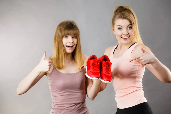 Två kvinnor presenterar sportkläder utbildare skor — Stockfoto