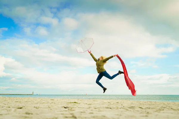 Happy woman jumping with scarf on beach — Stock Photo, Image