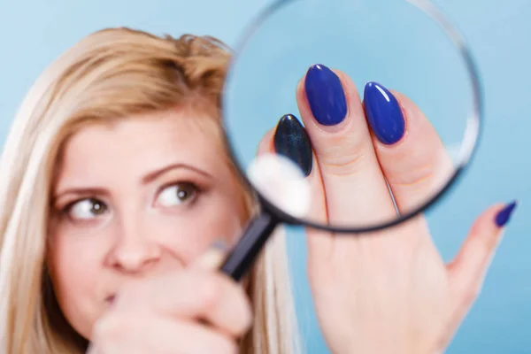 Woman looking at nails through magnifying glass — Stock Photo, Image