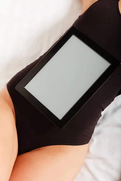 Sexy chica perezosa acostada con tableta touchpad en la cama — Foto de Stock