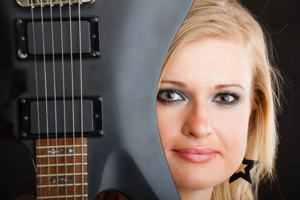 Blonde woman holding electric guitar, black background — Stock Photo, Image