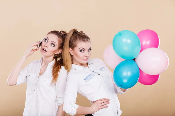 Two girls with mobile phone and balloons — Stock Photo, Image