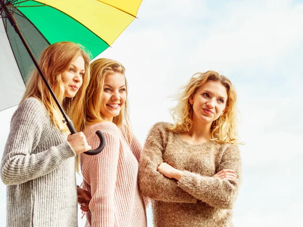 Tres mujeres bajo paraguas colorido — Foto de Stock