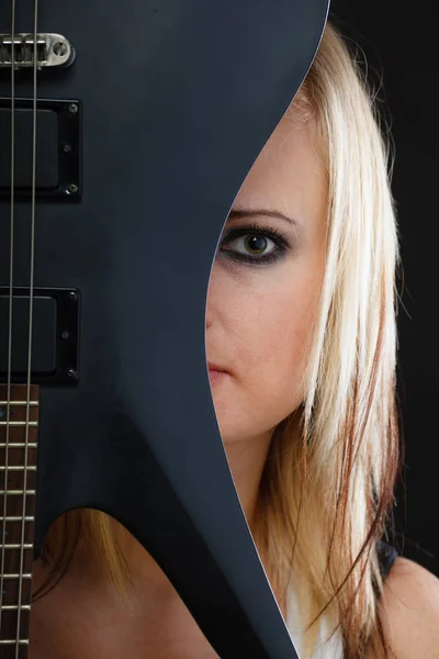 Blonde woman holding electric guitar, black background — Stock Photo, Image