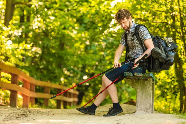 Escursionista uomo con zaino appoggiato su panchina nel sentiero forestale — Foto Stock