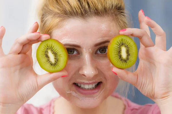 Wanita memiliki topeng gel di wajah memegang kiwi — Stok Foto